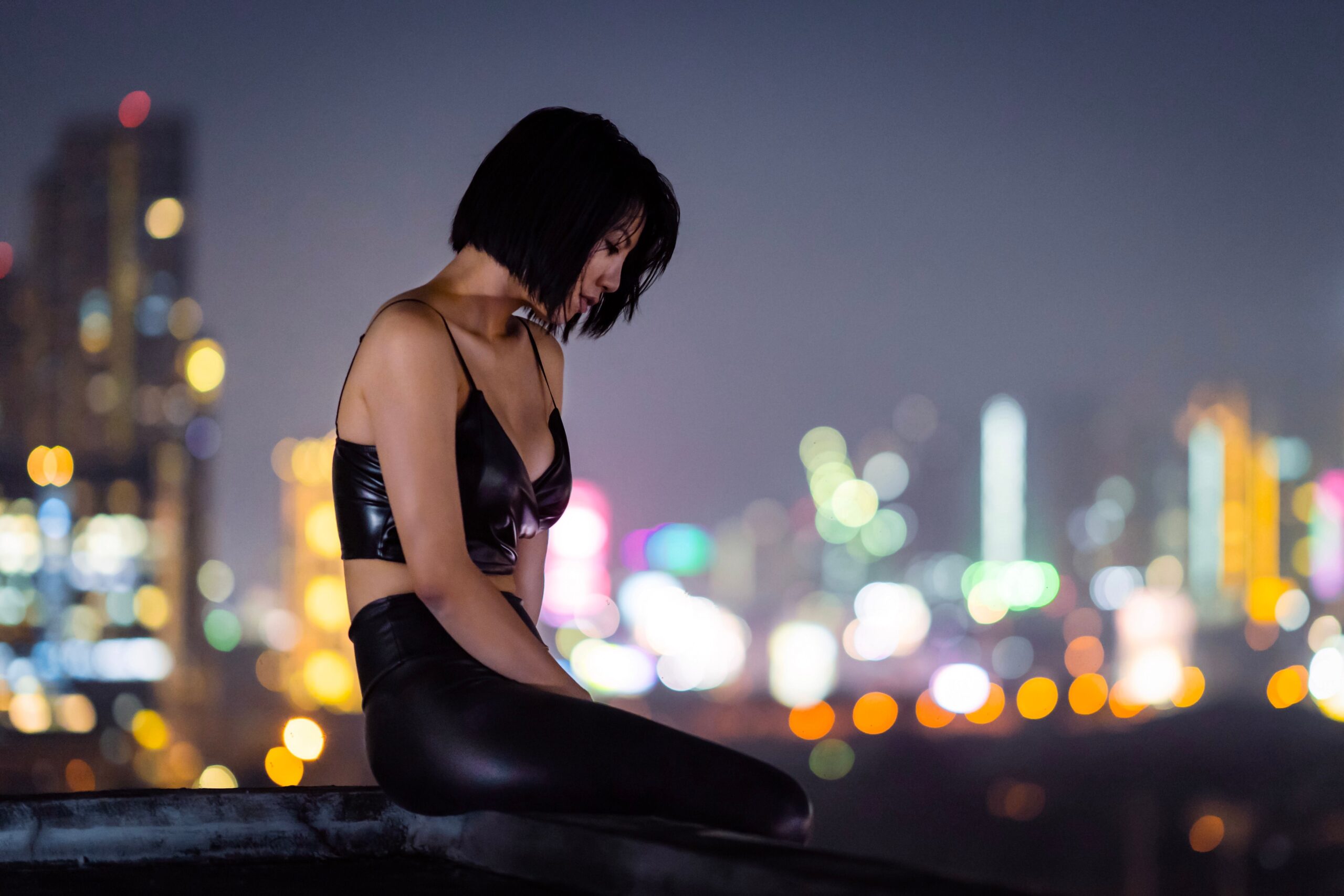 Stylish woman on a rooftop with city lights, evoking the modern independent lifestyle