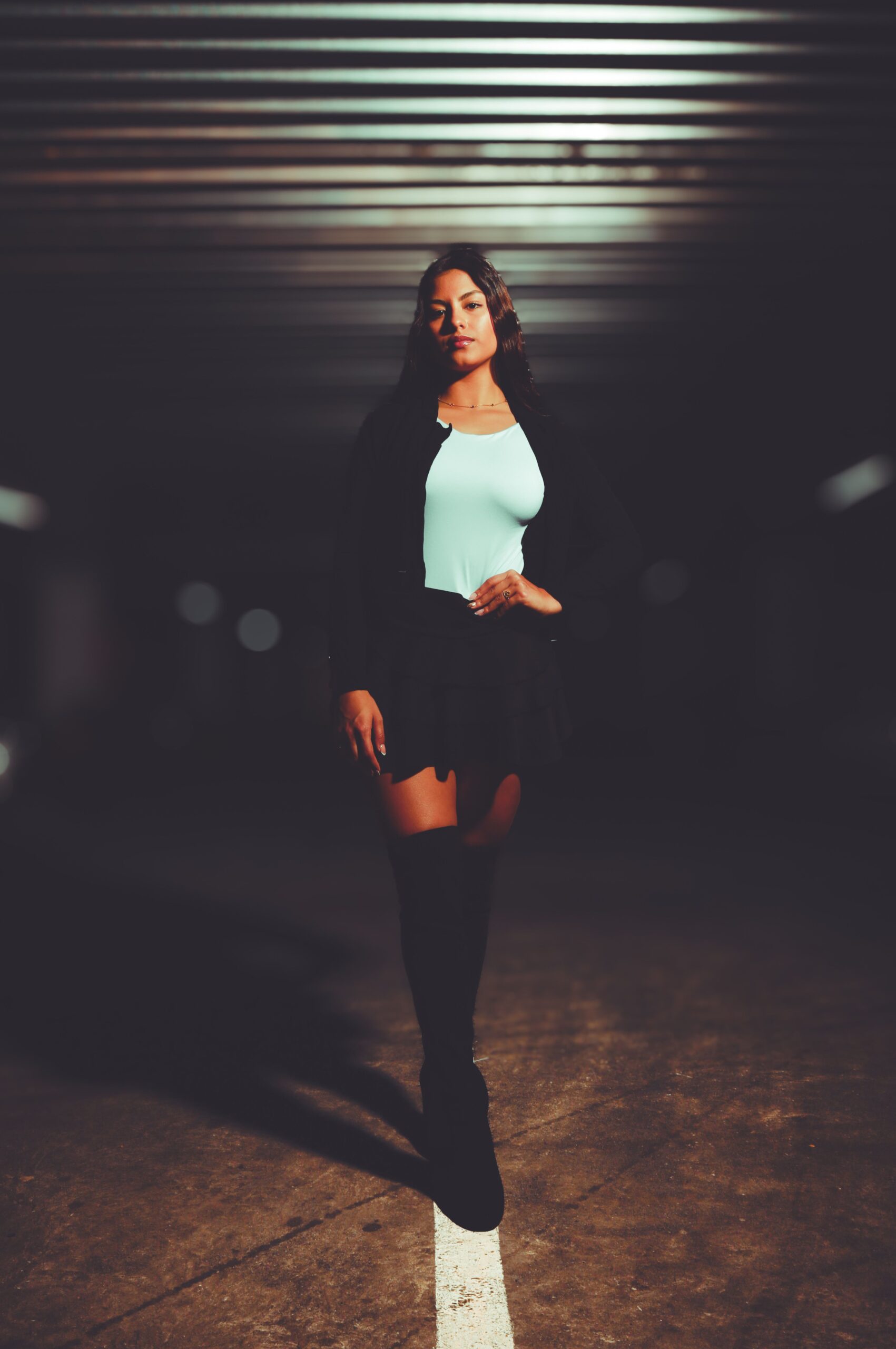 Woman standing confidently in a dimly lit urban environment, exuding independence and self-assurance