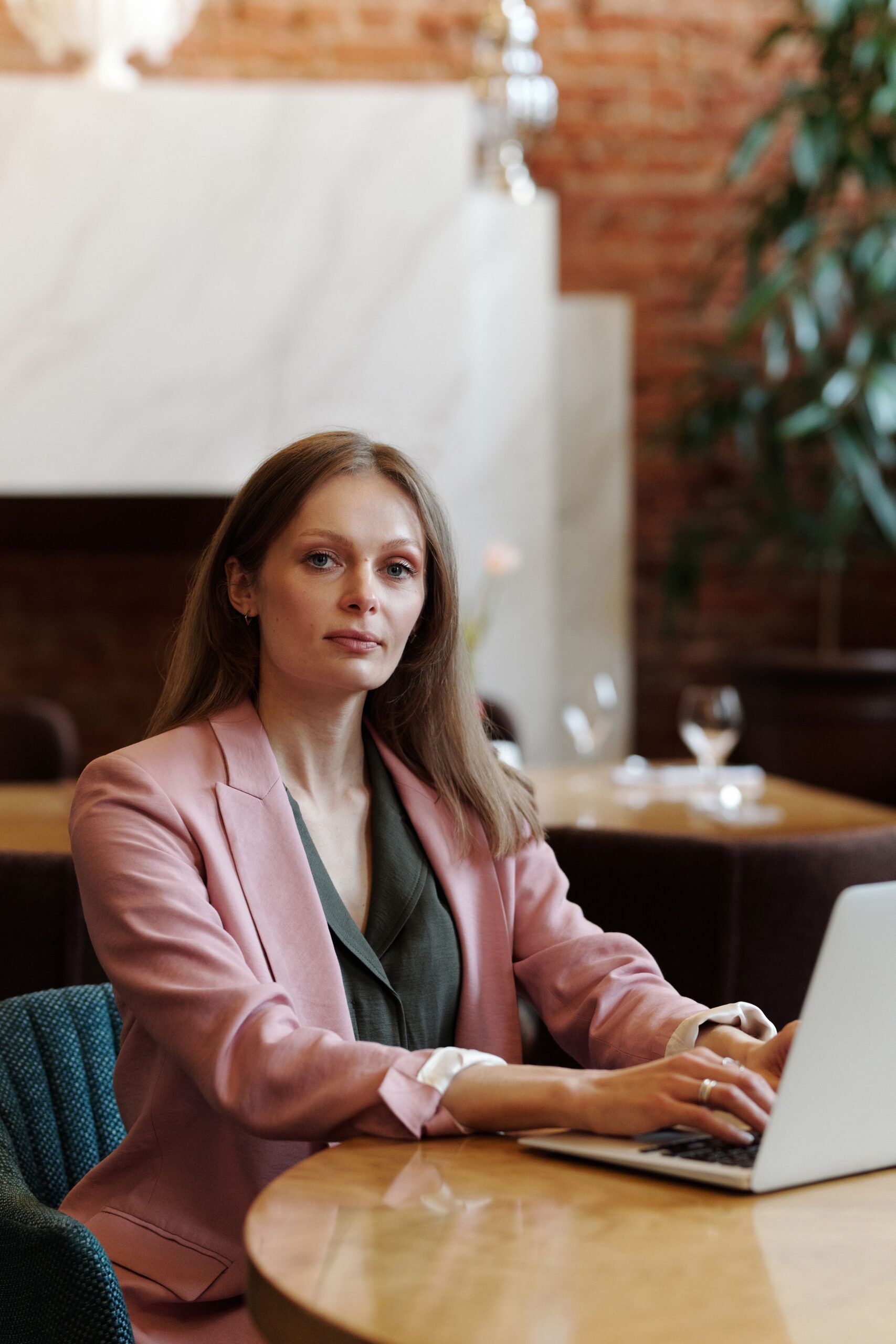 Confident woman working remotely on a laptop in a stylish cafe setting, illustrating independent entrepreneurship