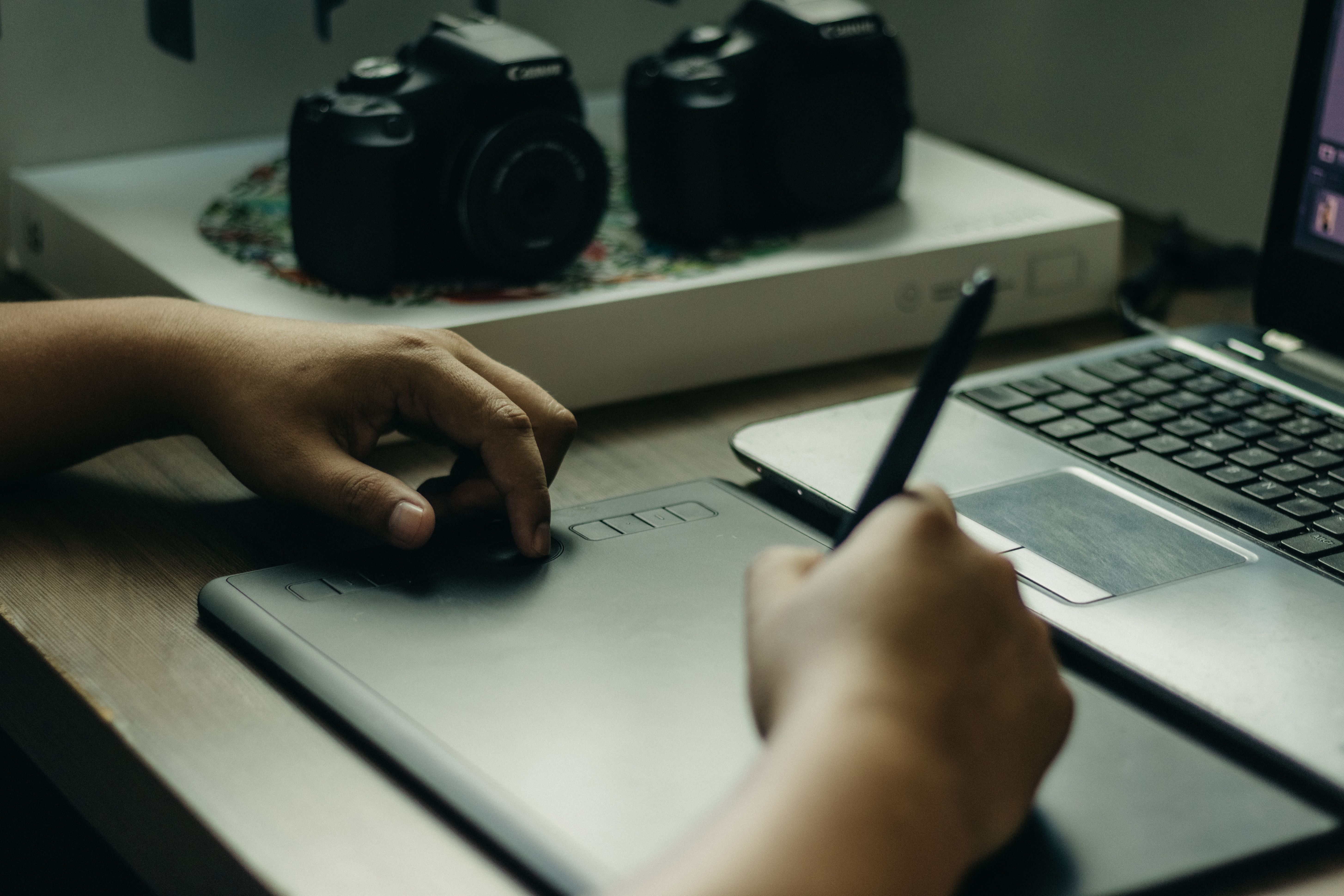 Cozy creative workspace with a graphic tablet, pen, and laptop for digital content creation