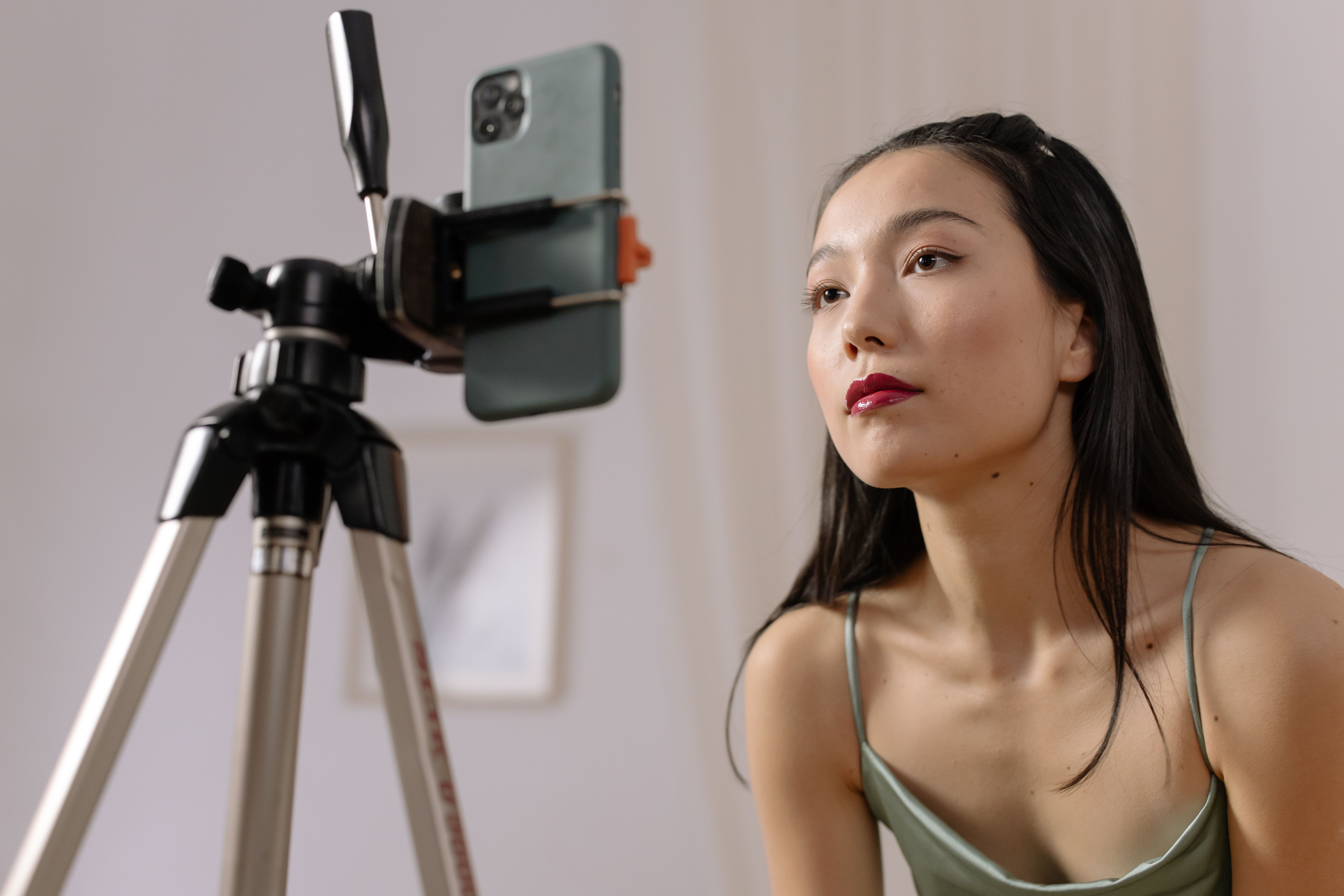 Woman recording a vlog indoors using a smartphone mounted on a tripod
