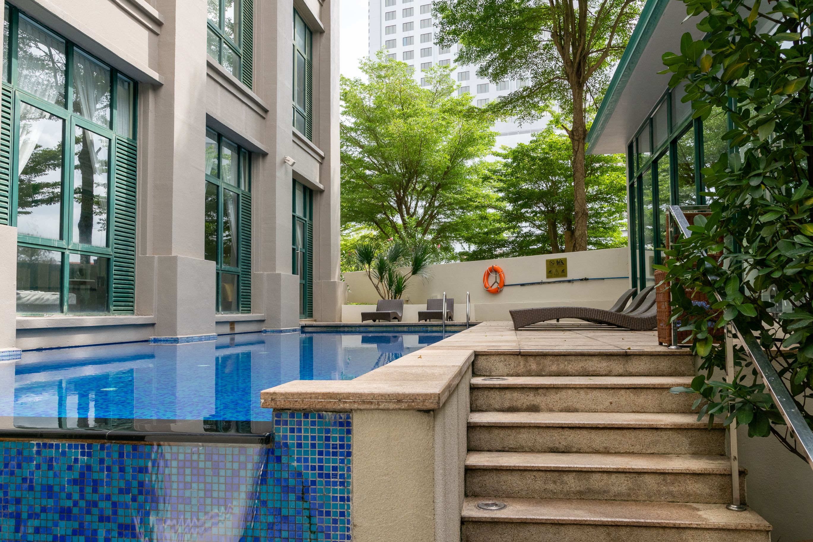 Contemporary poolside retreat framed by lush greenery, evoking the resort-style amenities of a prestige residence.